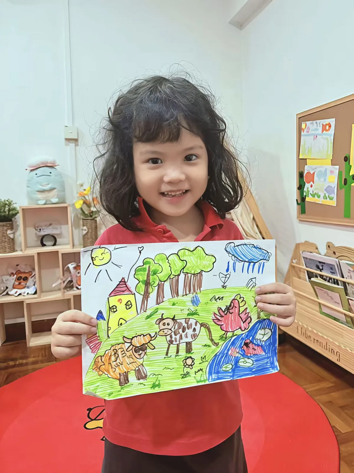 Child proudly displaying creative artwork drawing at MapleBear Jurong West Canadian curriculum preschool