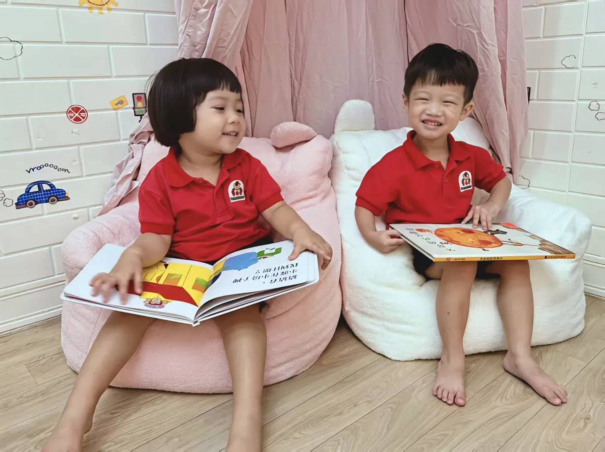 Children reading bilingual storybooks in a cozy reading corner at MapleBear Jurong West childcare centre
