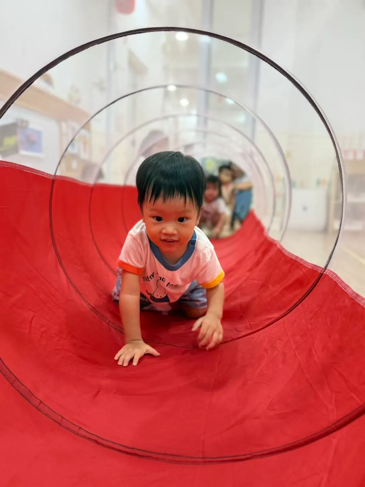 Toddler playing with indoor play tunnel activities at MapleBear Jurong West bilingual preschool childcare centre